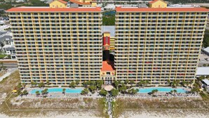 A large hotel with multiple floors, a central pool, and a beach area. - ☀️BeachFront-Tiki Bar-Pools-Calypso 2-1102☀️ (Panama City Beach)
