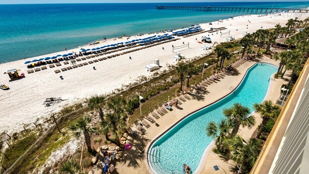 A beach resort with a swimming pool, beach umbrellas, and a pier. - ☀️BeachFront-Tiki Bar-Pools-Calypso 2-1102☀️ (Panama City Beach)