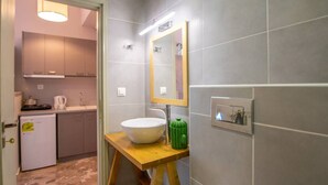 Une cuisine de taille réduite, dotée d’un évier blanc, d’un plan de travail en bois et d’un objet décoratif vert.