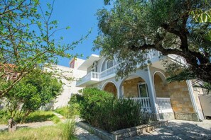 A two-story building with a balcony, stone walls, and a garden area. - Immaculate 1-bed House in Zakynthos (Zakynthos)