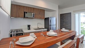 Eine moderne Küche mit Holzausstattung, einer Mikrowelle, einem Kühlschrank und einem Essbereich mit einem Holztisch für zwei Personen.