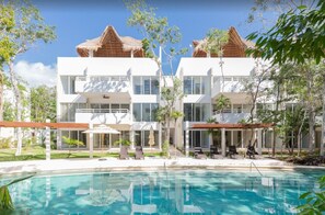 Un hôtel moderne doté d’une piscine, d’un espace extérieur aménagé et d’un jardin tropical.