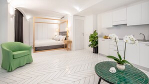 A modern hotel room with a green sofa, a bed with a wooden frame, a small table with a green mosaic top, and white orchid flowers in a vase. - Luxury Villa with Penthouse, Pools and Sea View (Sant'Agnello)
