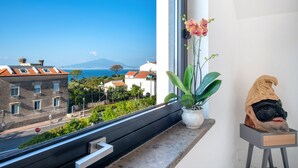 A balcony with a view of the sea and buildings, a potted plant, and a sculpture. - Luxury Villa with Penthouse, Pools and Sea View (Sant'Agnello)