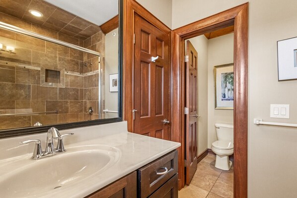 A bathroom with a large mirror, a sink, and wooden doors leading to another room. - WV31 Sky Surfer by First Flight Rentals (Rodanthe)