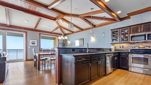 A modern kitchen with wooden beams, stainless steel appliances, and a large island. - WV31 Sky Surfer by First Flight Rentals (Rodanthe)