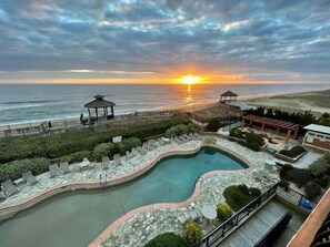 A pool area with a gazebo, lounge chairs, and a view of the sunset over the ocean. - CSC4I The Platinum Suite by First Flight Rentals (Kill Devil Hills)