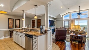 Une cuisine spacieuse avec un grand îlot central, un coin repas offrant une vue agréable et un salon doté d’une cheminée.