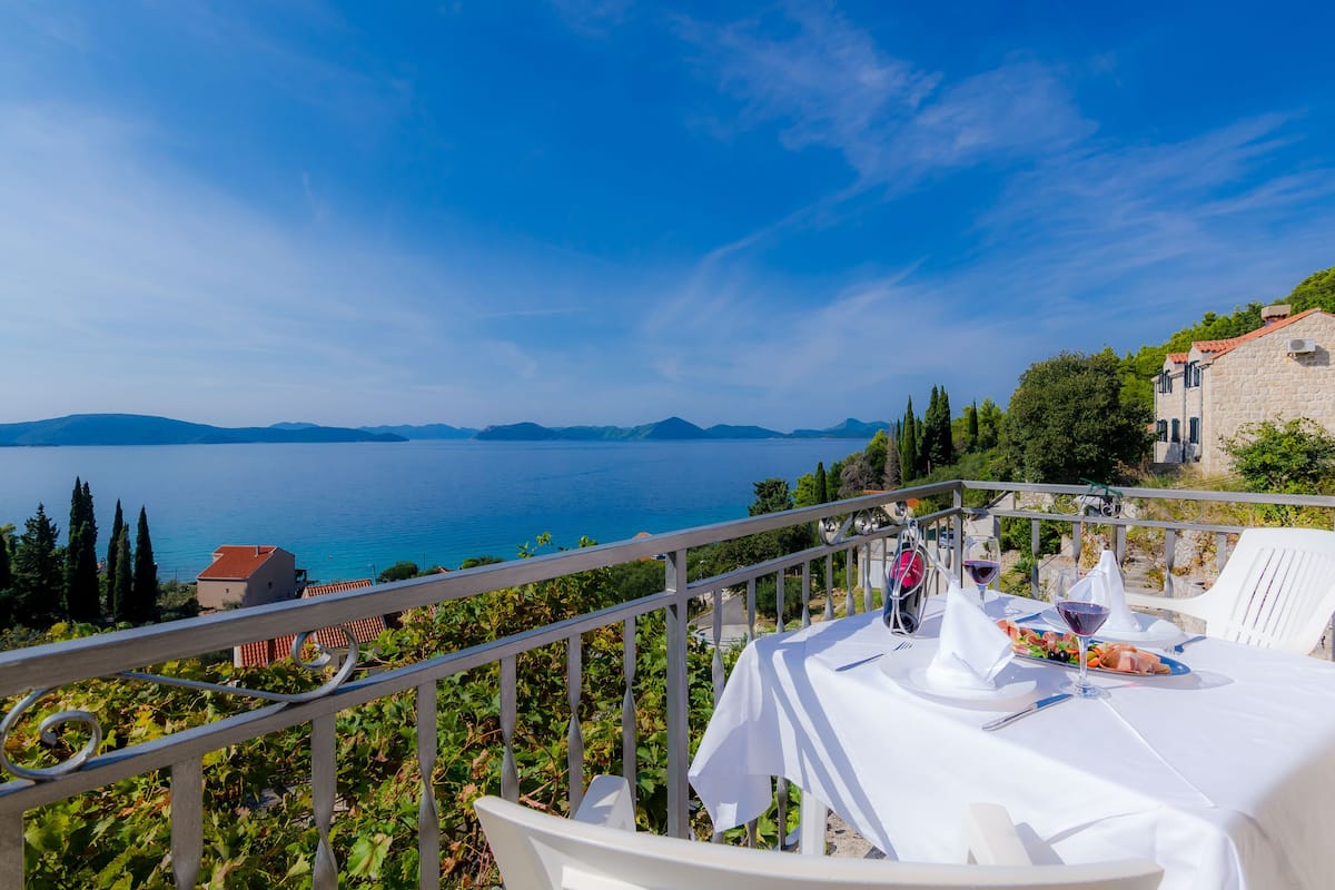 Una mesa lista para comer con vista al mar y montañas a lo lejos.