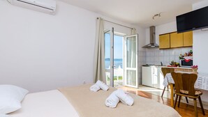Ein Hotelzimmer mit Bett, Sessel, Tisch, Küchenzeile und einem Balkon mit Aussicht.