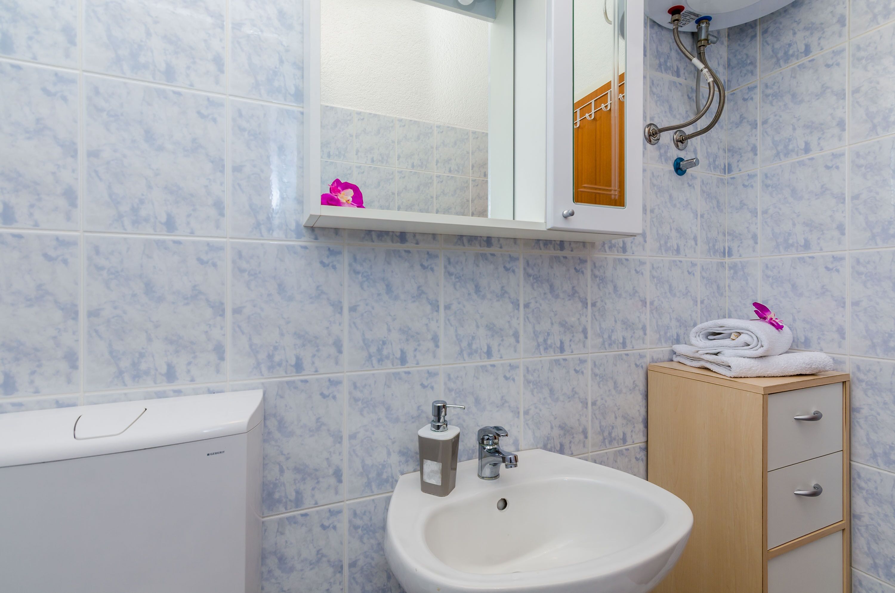 Une salle de bain avec un lavabo blanc, un meuble en bois et un miroir.