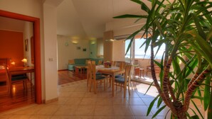 A spacious living area with a dining table, chairs, and a large plant. - Apartment Villa Molina (Zupa dubrovacka)