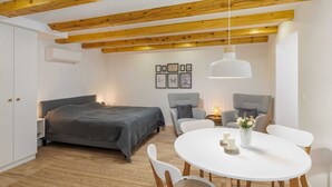 Ein Schlafzimmer mit Bett, Nachttischen, einem runden Esstisch mit Stühlen, einer Hängeleuchte und einer Wand-Klimaanlage.