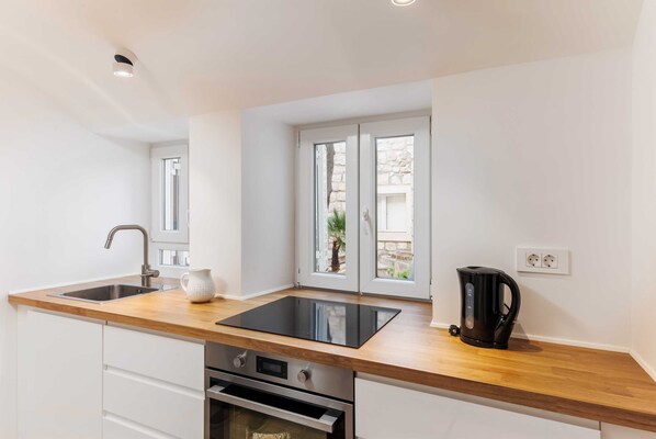 Una cocina moderna con encimera de madera, electrodomésticos de acero inoxidable y una ventana con vistas a zonas verdes.