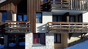 A modern multi-story building with wooden balconies and stone accents.