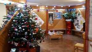 A room with a Christmas tree, wooden walls, a staircase, and a tiled floor.