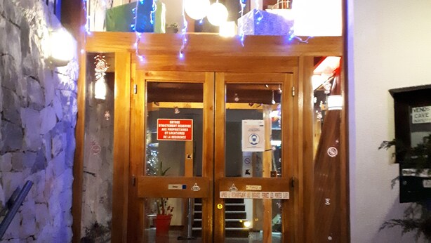 A wooden double door with glass panels, a sign indicating a restricted area, and a small step leading up to the entrance.