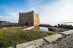 Une tour de pierre historique, entourée de douves et précédée d’une pelouse.