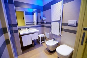 Une salle de bain moderne avec un grand miroir, un lavabo, un bidet et des toilettes.