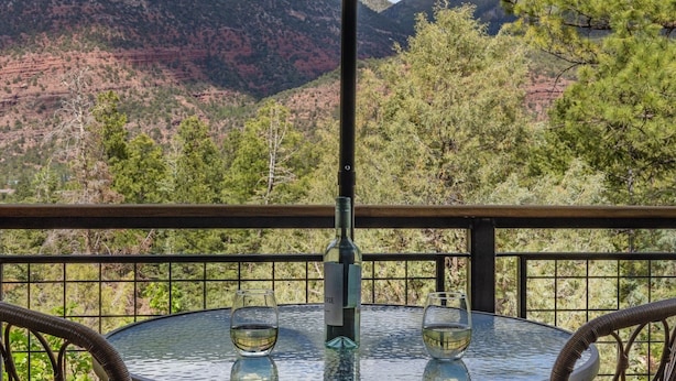 A table with two glasses and a bottle, set against a mountainous backdrop.