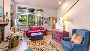 A cozy living room with a red sofa, blue armchair, and a patterned rug.