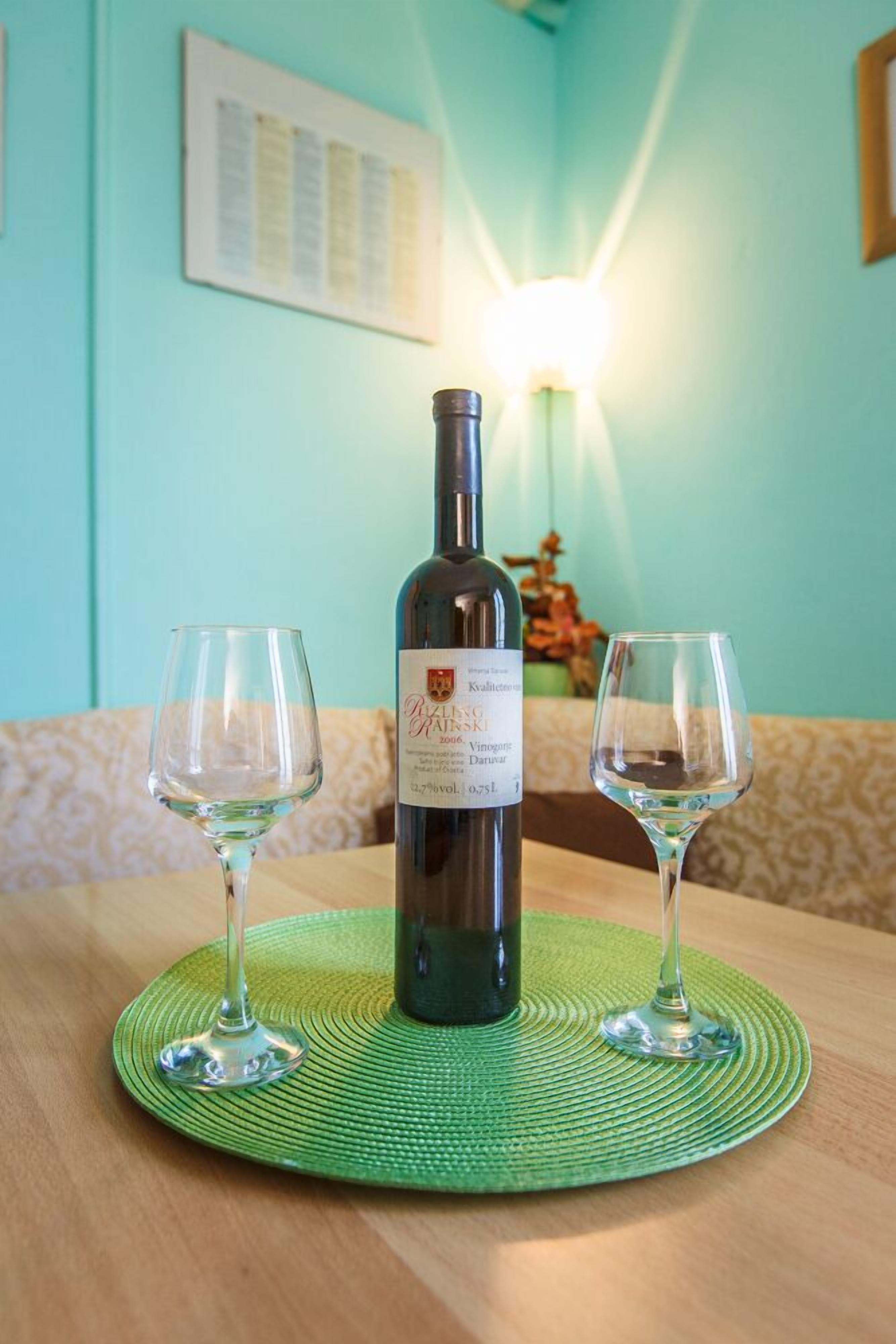 A bottle of wine on a table with two glasses.