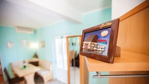 A framed picture of stones on a shelf in a room with teal walls, a wooden table, and a door in the background. - Apartments Irene's Place (Solta)