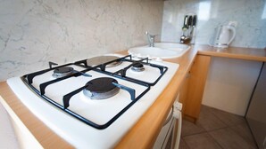 A kitchen with a white stove, two sinks, and wooden cabinets. - Apartments Irene's Place (Solta)