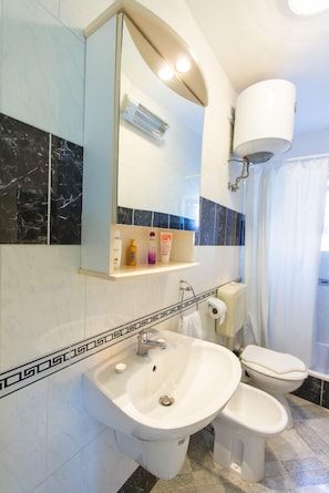 Ein modernes Badezimmer mit großem Spiegel, zwei Waschbecken, Toilette und Duschbereich.