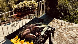 Un barbecue avec différentes sortes de viandes et de légumes, installé sur un balcon donnant sur un paysage magnifique.