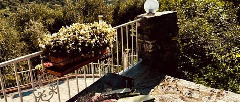 A barbecue grill with various meats and vegetables on a balcony overlooking a scenic landscape.