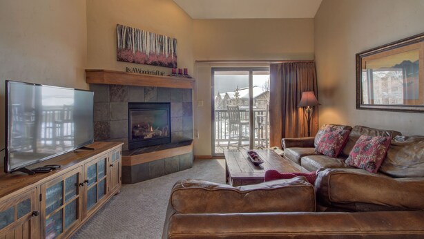 A living room with a fireplace, a television, a sofa, and a coffee table. - Spacious 3-Bedroom + Loft Condo at Timber Run – Perfect for Families and Groups! (Steamboat Springs)