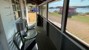 A covered porch with a view of a lake, a table, and chairs. - Lakefront  Yellow Cottage (Northwood)