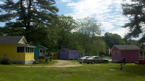 A campground with several small cabins, a gravel path, and a grassy area. - Lakefront  Yellow Cottage (Northwood)