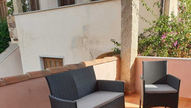 A patio area with wicker furniture, including a sofa and chairs, and a glass table. - A stone's throw from the center (San Teodoro)