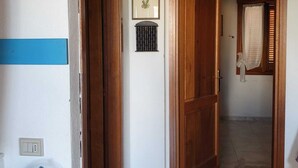 A hallway with wooden doors, a framed picture, and a ceiling vent. - A stone's throw from the center (San Teodoro)