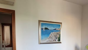 A room with a sofa bed, a painting of a coastal scene, and a fan. - A stone's throw from the center (San Teodoro)