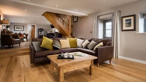 Een moderne woonkamer met een houten salontafel, een leren bank en een trap.