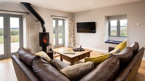 Een moderne woonkamer met een open haard, een leren bank, een houten salontafel en een flatscreen televisie.