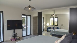 A modern bedroom with a large bed, a flat-screen TV, and a large mirror. - Beautiful house with heated pool overlooking Barjac (Barjac)
