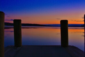 A wooden dock extending into calm water during twilight. - Rustic Charm: Pewaukee Lake Cabin, Sauna & Hot Tub (Pewaukee)