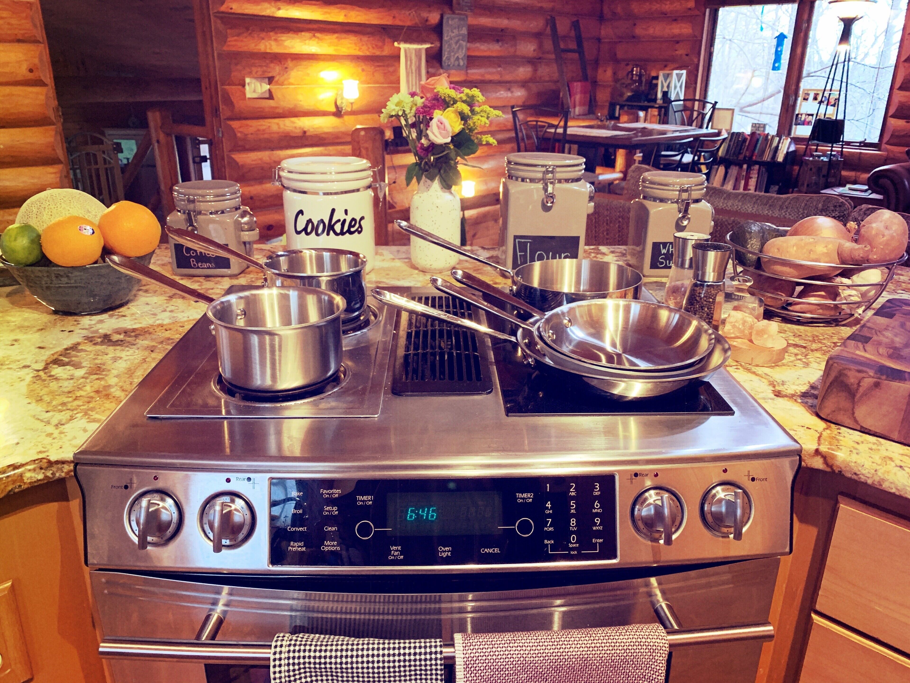 A kitchen with a stove, pots, and a bowl of oranges.
