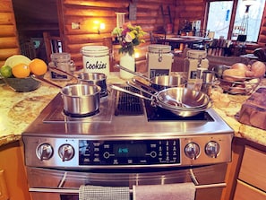 A kitchen with a stove, pots, and a bowl of oranges. - Rustic Charm: Pewaukee Lake Cabin, Sauna & Hot Tub (Pewaukee)
