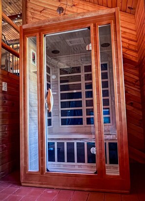 A wooden cabin with a large glass door leading to a room with multiple windows. - Rustic Charm: Pewaukee Lake Cabin, Sauna & Hot Tub (Pewaukee)