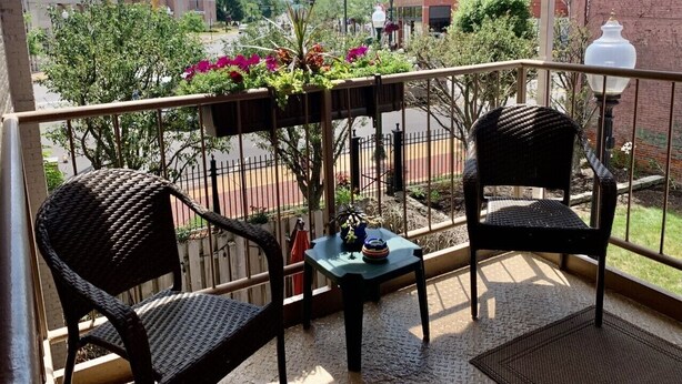 Ein Balkon mit Korbstühlen, einem kleinen Tisch und Topfpflanzen.