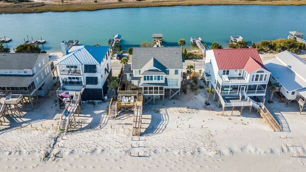 A coastal property with beachfront villas, a dock, and a view of the ocean and wetlands.