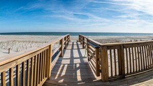 A wooden boardwalk leading to a sandy beach with a clear sky.