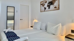 Ett hotellrum med en stor säng, en världskarta som konstverk, en spegel och ett nattduksbord med en lampa.