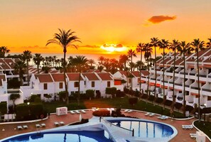 A resort with a swimming pool, palm trees, and a sunset view. - Magnificent duplex renovated in Parque Santiago II (Arona)