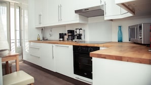 Una cocina moderna con armarios blancos, encimera de madera, horno empotrado y cafetera.